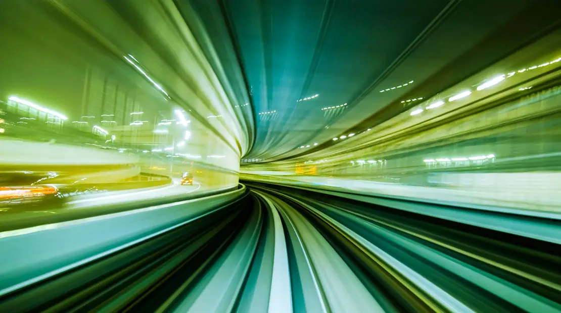 Linea ferroviaria ripresa in movimento con effetto di scie luminose, simbolo di velocità ed energia.