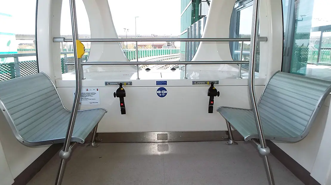 Interno dello shuttle Pisa Mover con sedili laterali e area attrezzata per persone con disabilità.