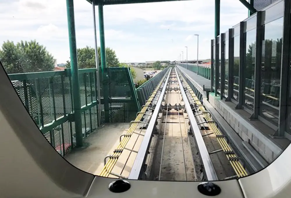 Vista frontale dal treno PisaMover sui binari sopraelevati che conducono alla stazione.