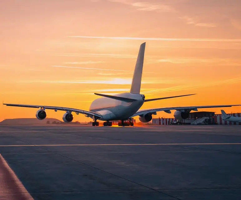 Un aereo di linea parcheggiato sulla pista dell’aeroporto di Pisa al tramonto.