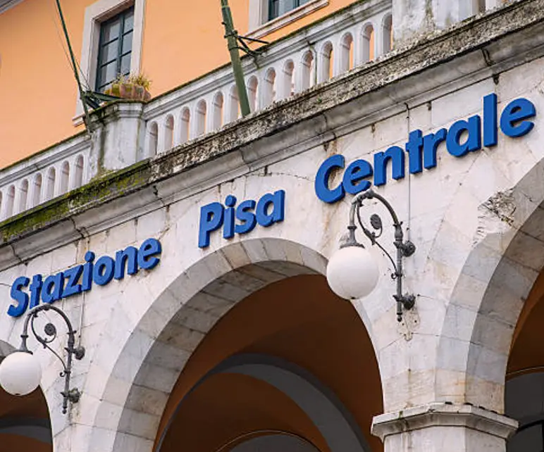 Ingresso della stazione Pisa Centrale con insegna blu sulla facciata ad archi.