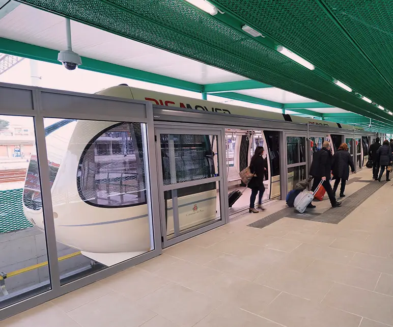 Passeggeri in salita e discesa dal convoglio Pisa Mover alla stazione.